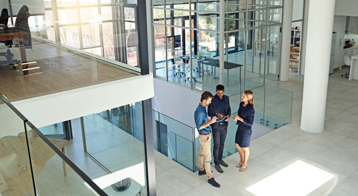 Colleagues in modern office lobby discussing on tablet