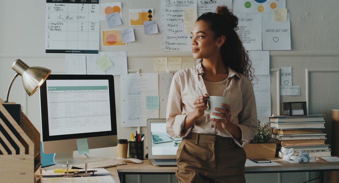 Focused businesswoman in her NYC startup office, contemplating with coffee in hand.