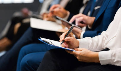 Real estate professionals at NYC convention center, taking notes.