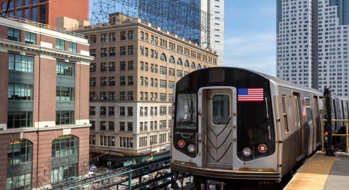 Elevated subway station with NYC skyline and financial buildings.