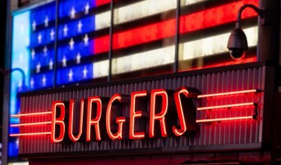 A neon 'Burgers' sign in NYC, symbolizing evolving restaurant leasing opportunities.