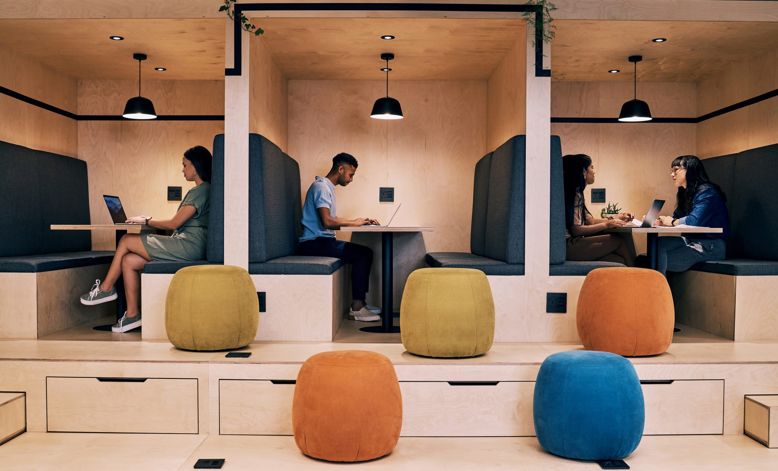 People having conversations in booth spaces with tables and padded benches.