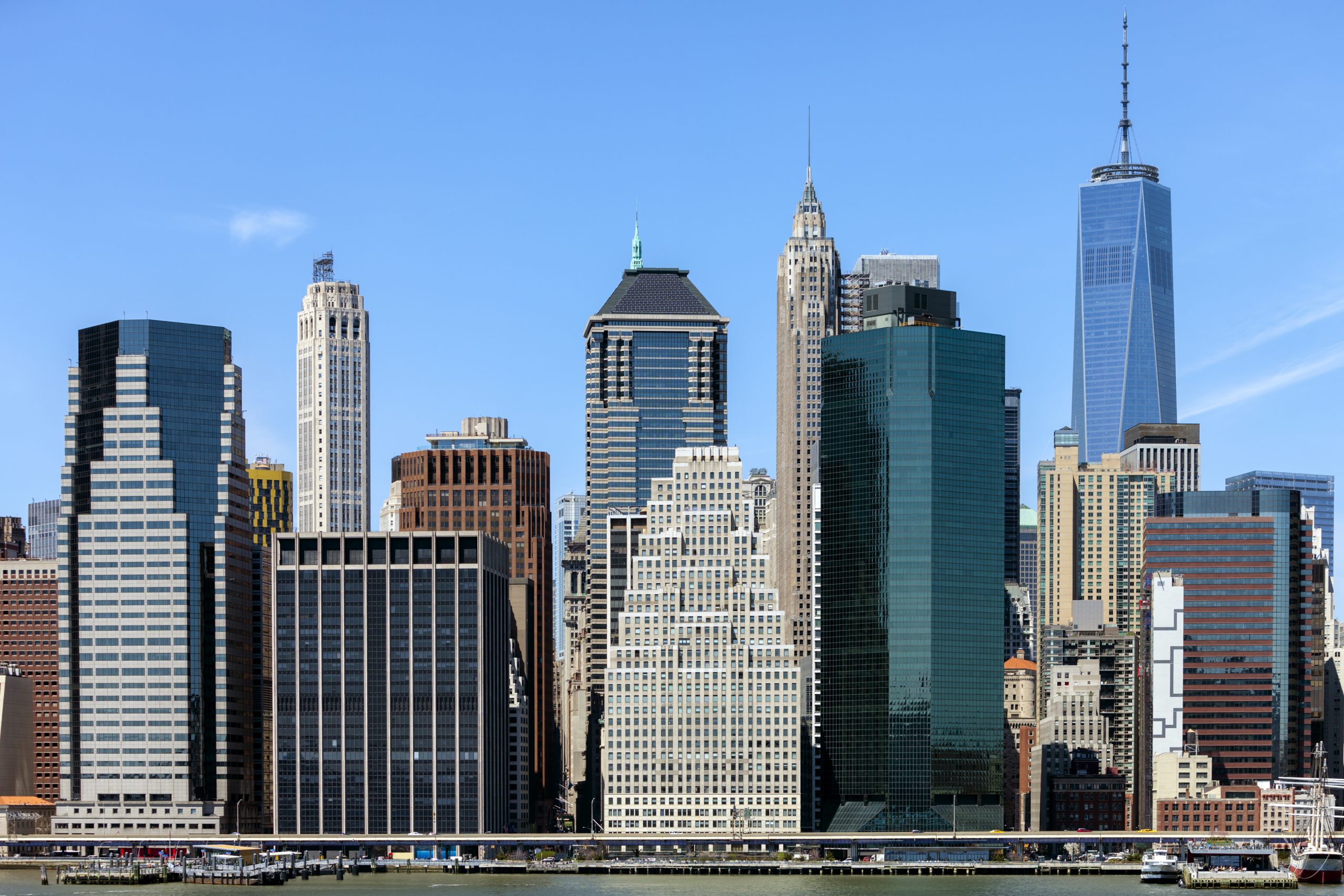 NYC, densely packed Lower Manhattan skyscrapers under a clear blue sky.