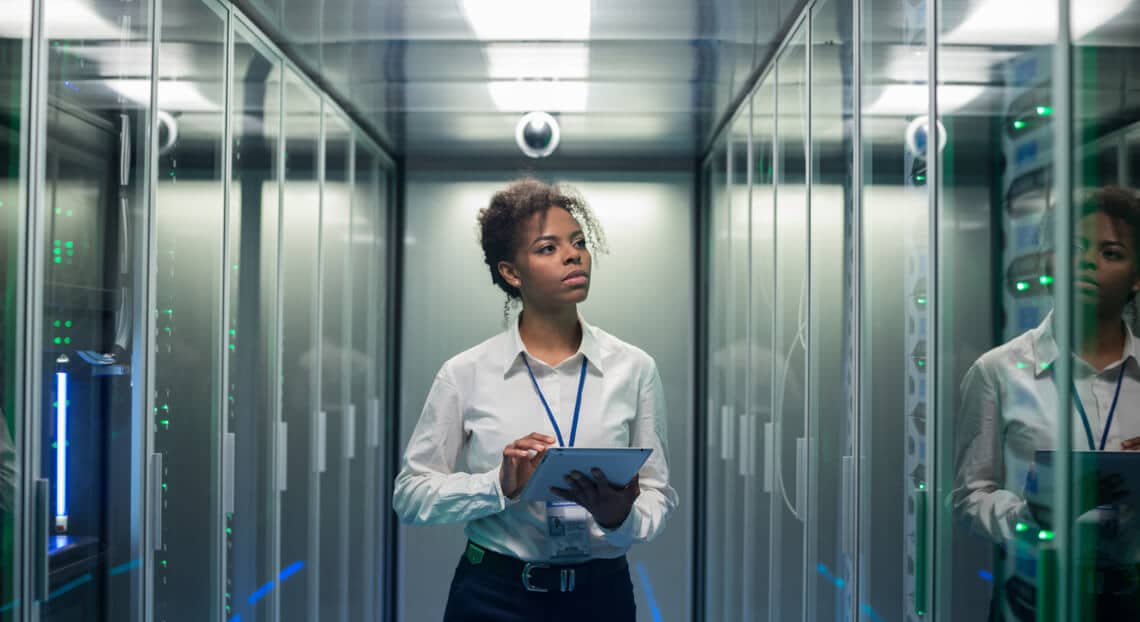 Woman diagnosing server hardware for improved telecom in NYC office space.