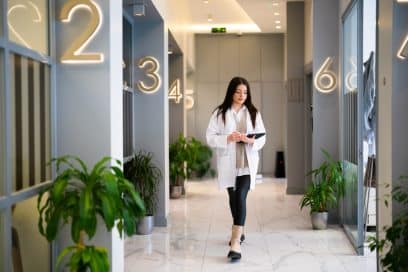 A female healthcare worker navigating an NYC clinic corridor.