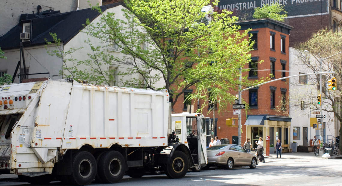 NYC garbage truck parked in Tribeca, depicting waste management issues of Manhattan.