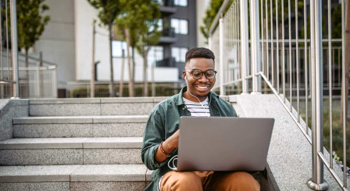 New York City CRE Learner on Laptop at Office Building Stairs