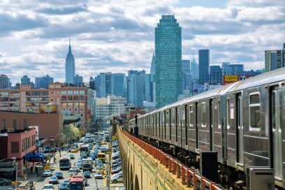 Bustling Queens subway and iconic Manhattan skyline.