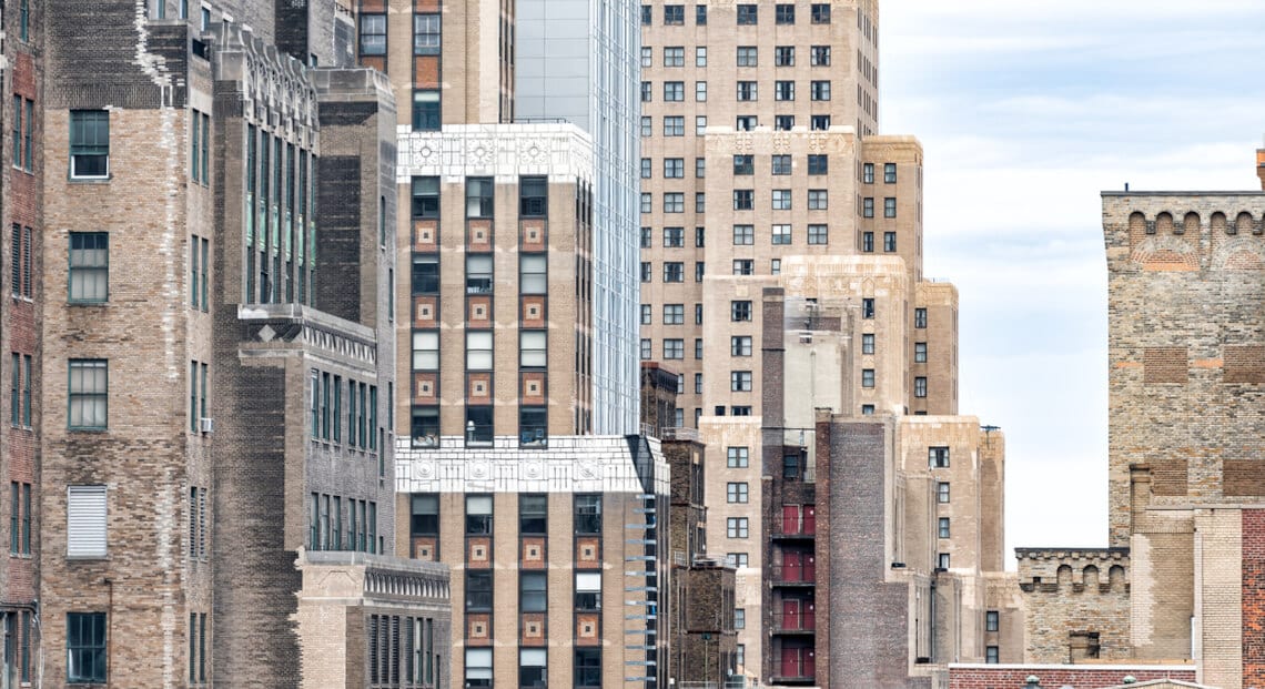 Aerial view of vintage brick skyscrapers in NYC, including Nelson Tower, seen through windows.