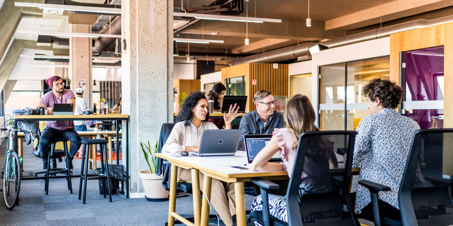 Business Professionals having a Friendly Discussion in a Large Coworking Office Space.