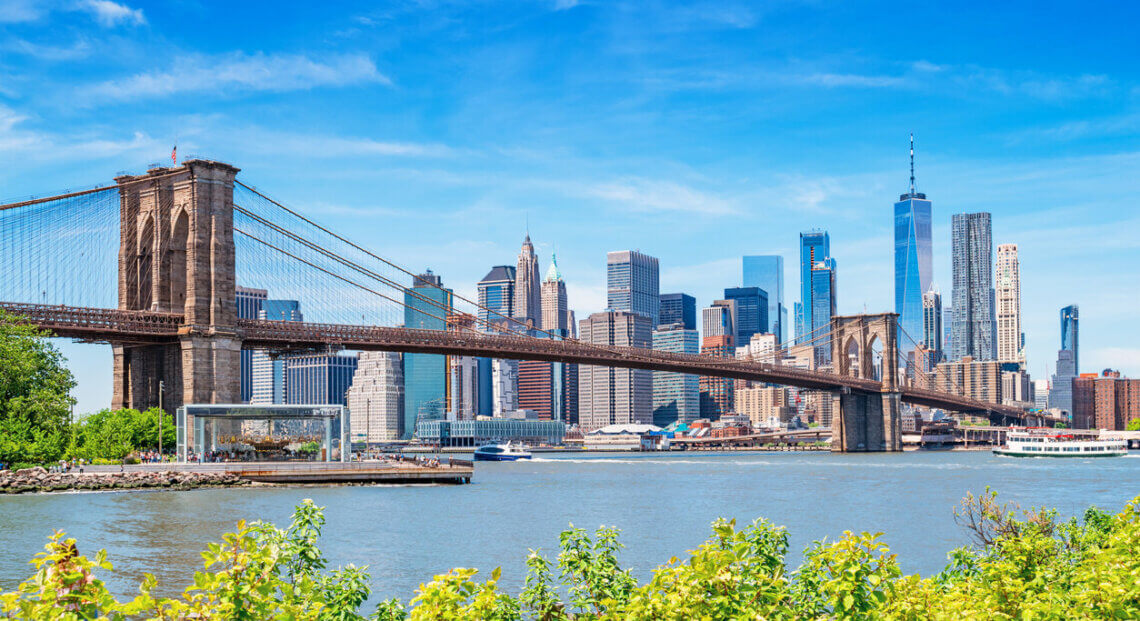 Lower Manhattan skyline and Brooklyn Bridge as seen from Brooklyn on sunny day.