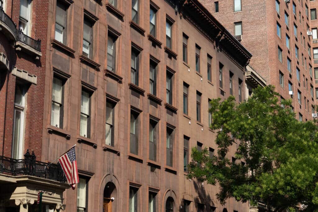 Old stone & brick buildings in Murray Hill, NYC with a hanging American flag 