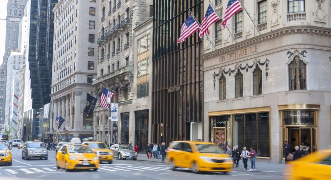 A photo of New York's 5th Avenue, with multiple luxury stores visible in the background.