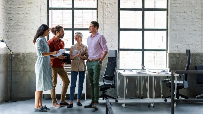 Group of happy businesspeople chatting in a loft-style open space office.