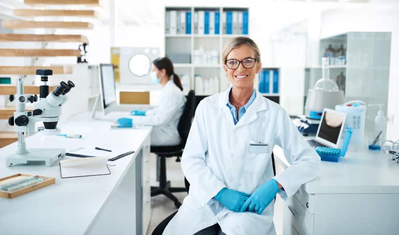 Scientist in a lab space seated at a table with a microscope