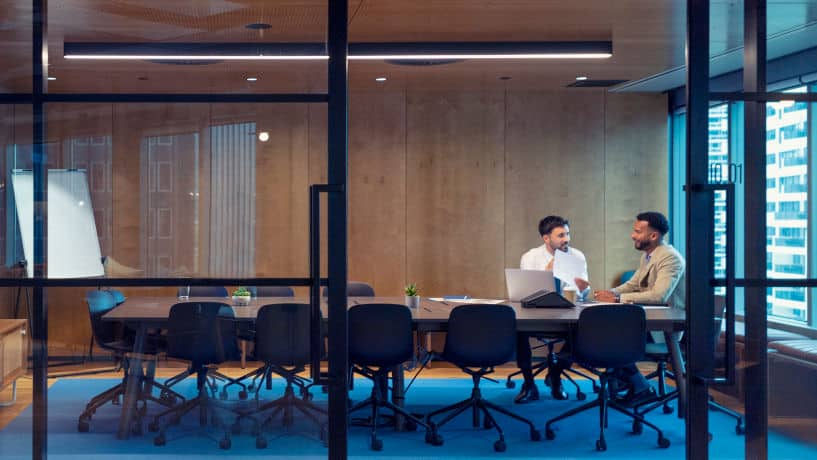 Business people with laptop and tablet in modern boardroom.