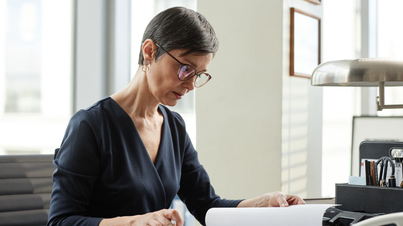 Mature lawyer working on a document at her desk in a private office, side view