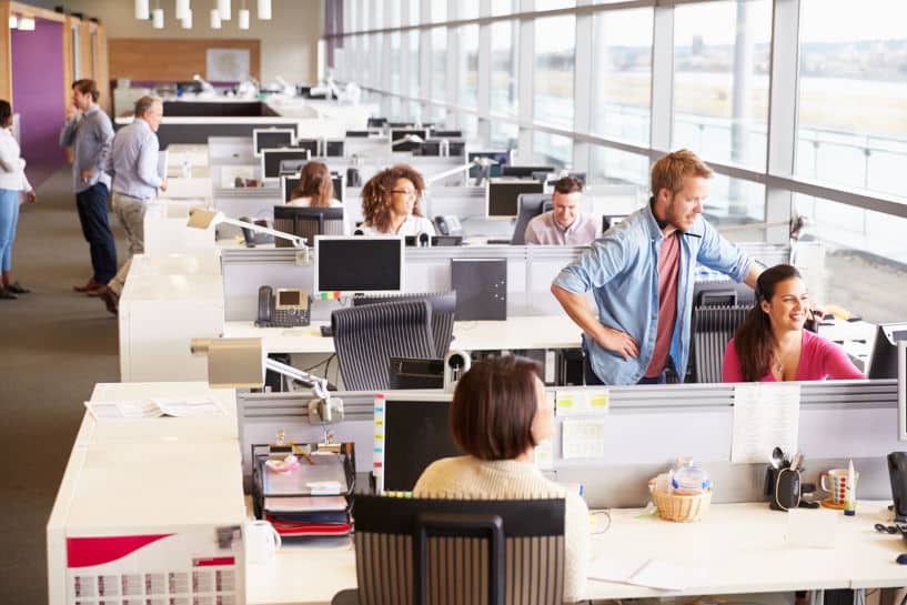 Bullpen in a commercial office: employees at tables engaged in team project