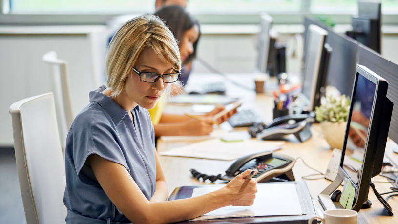 Female executive writing notes at desk in Manhattan office.