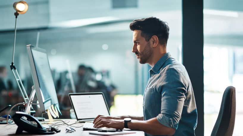 Young businessman at desk in modern office focused on computer work