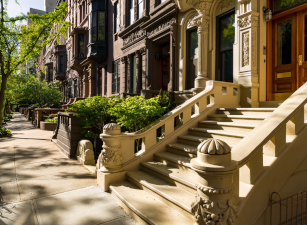Brownstones on Upper West Side street, showcasing Uptown Manhattan's charming real estate allure.