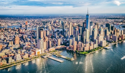 Aerial view of Lower Manhattan, NYC, under sunny skies, hinting at office market resurgence.