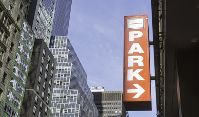 Large red "PARK" sign with right arrow on NYC city building.