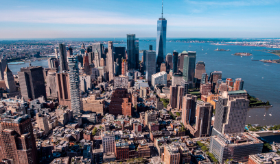 Aerial view of Lower Manhattan with skyscrapers, rivers, and Statue of Liberty.