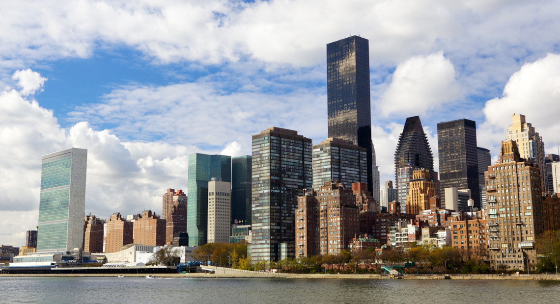 NYC skyline with skyscrapers, UN HQ, and varied buildings across river.