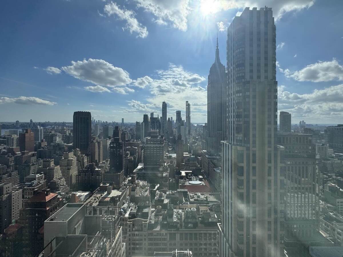 City skyline from 33rd Floor at 10 E 40th St, blue sky, clouds, sun.