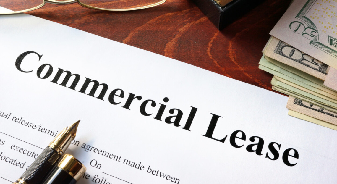 Commercial Lease document on desk with pen, glasses, and cash nearby.