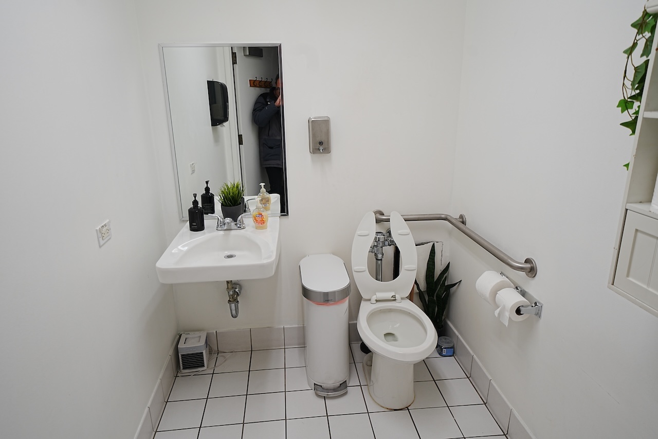 Clean bathroom at 515 Seventh Ave with white sink, toilet, mirror, and plants.