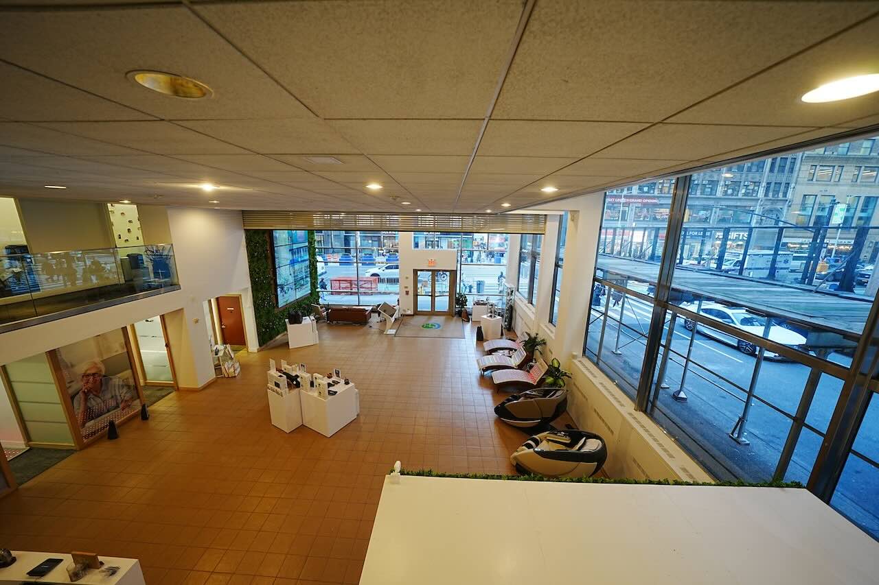 Modern showroom with large windows, tiled floors, white walls, and lounge chairs corner 515 Seventh; parked cars and buildings outside.