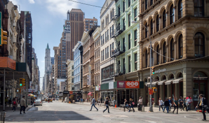 Busy SoHo street with pedestrians, historic lofts, shops, and cars.