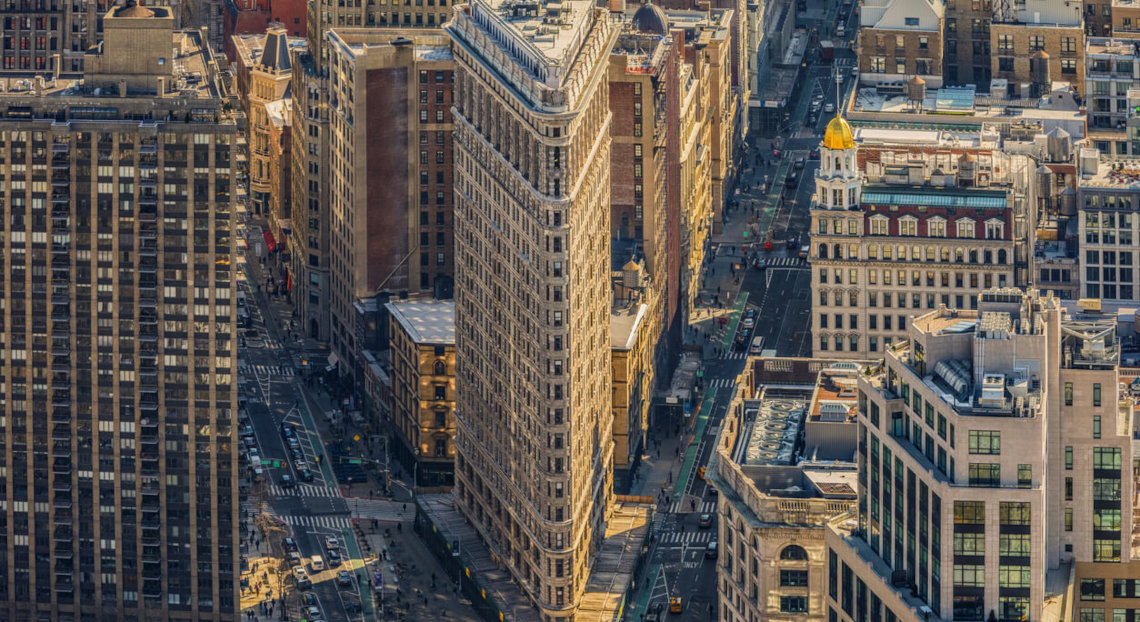 Aerial view of the Flatiron Building amid New York City streets and towers.