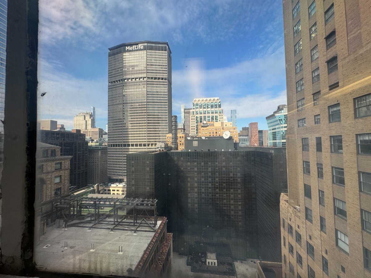 View through window of cityscape with MetLife skyscraper, blue sky, rooftops.