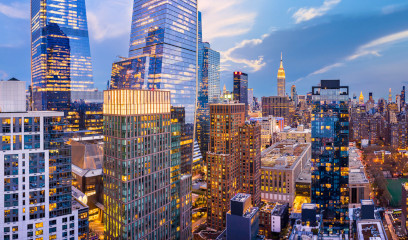 NYC cityscape at dusk with lit skyscrapers, Empire State Building visible.