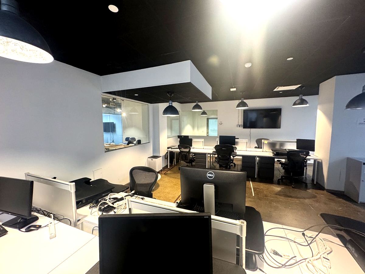 Open bullpen with black ceiling, pendant lights, and glass walls, 16th floor at 15 Maiden Lane