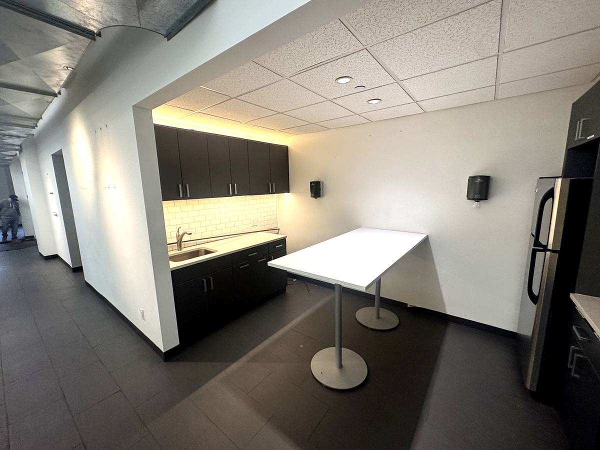 Pantry with dark cabinetry, subway tile, and standing table, 4th floor at 7 West 30th Street