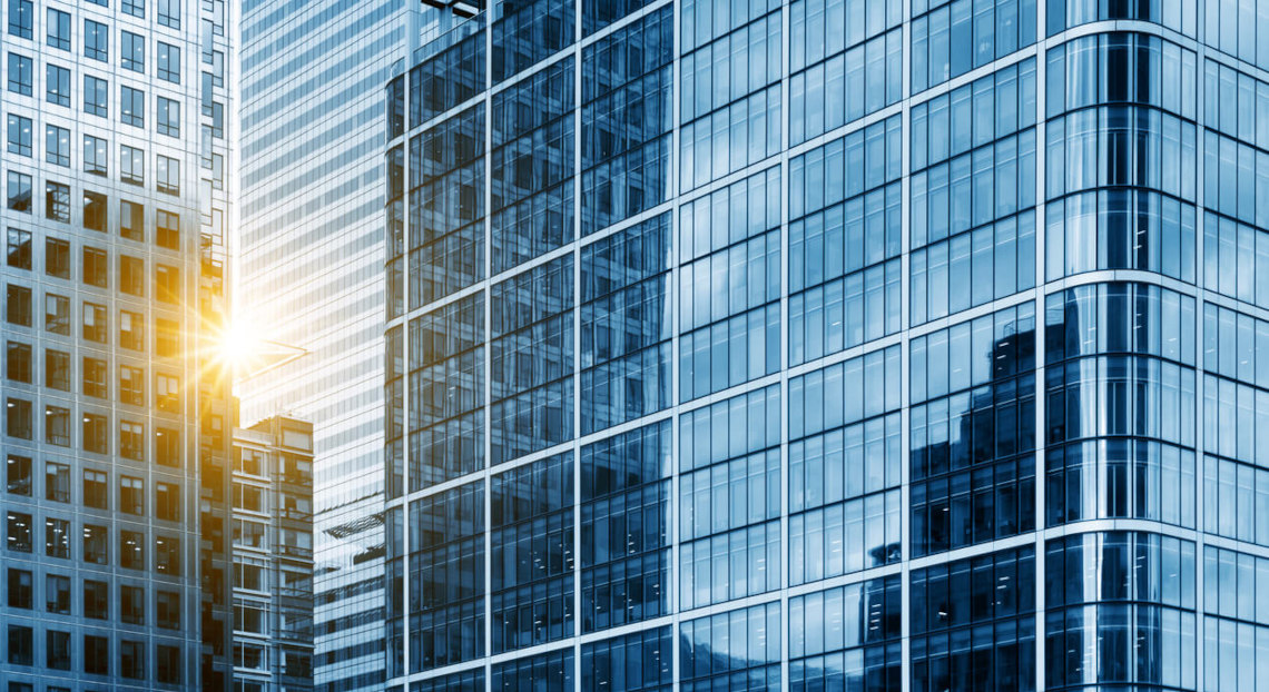 Glass skyscrapers reflect sunlight in a sleek blue NYC cityscape.