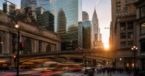 Grand Central and Chrysler Building at sunset, blurred traffic, people crossing.