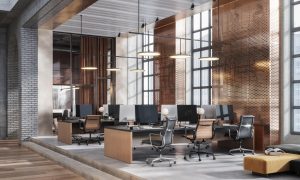 Modern open office with wooden desks, black chairs, large windows.