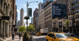 NYC street with yellow taxis, pedestrians, tall buildings, and billboard.
