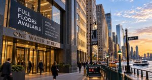 People walk past One Water Street in Lower Manhattan at sunset.