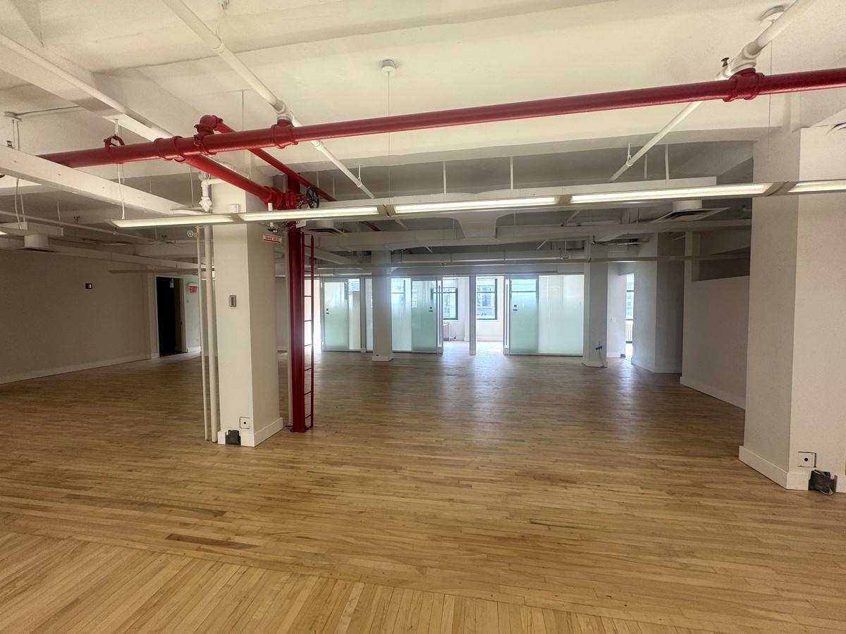 Loft area with exposed pipes and glass offices, 10th floor at 118 West 22nd Street