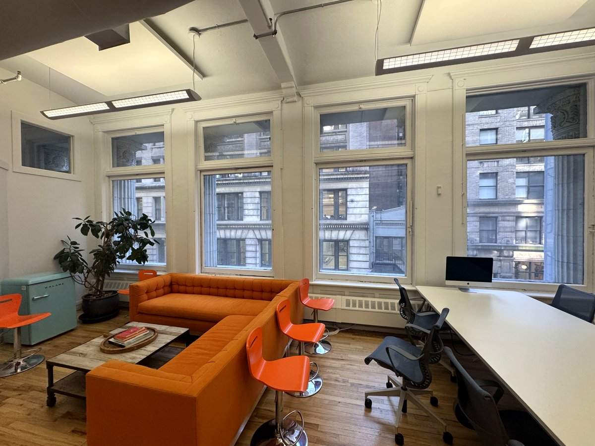 Orange sofa lounge beside a wall of windows, 5th floor at 3 West 18th Street