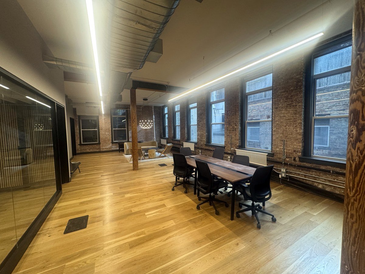 Open plan office with conference table, exposed brick, and linear lighting at 46 Greene Street