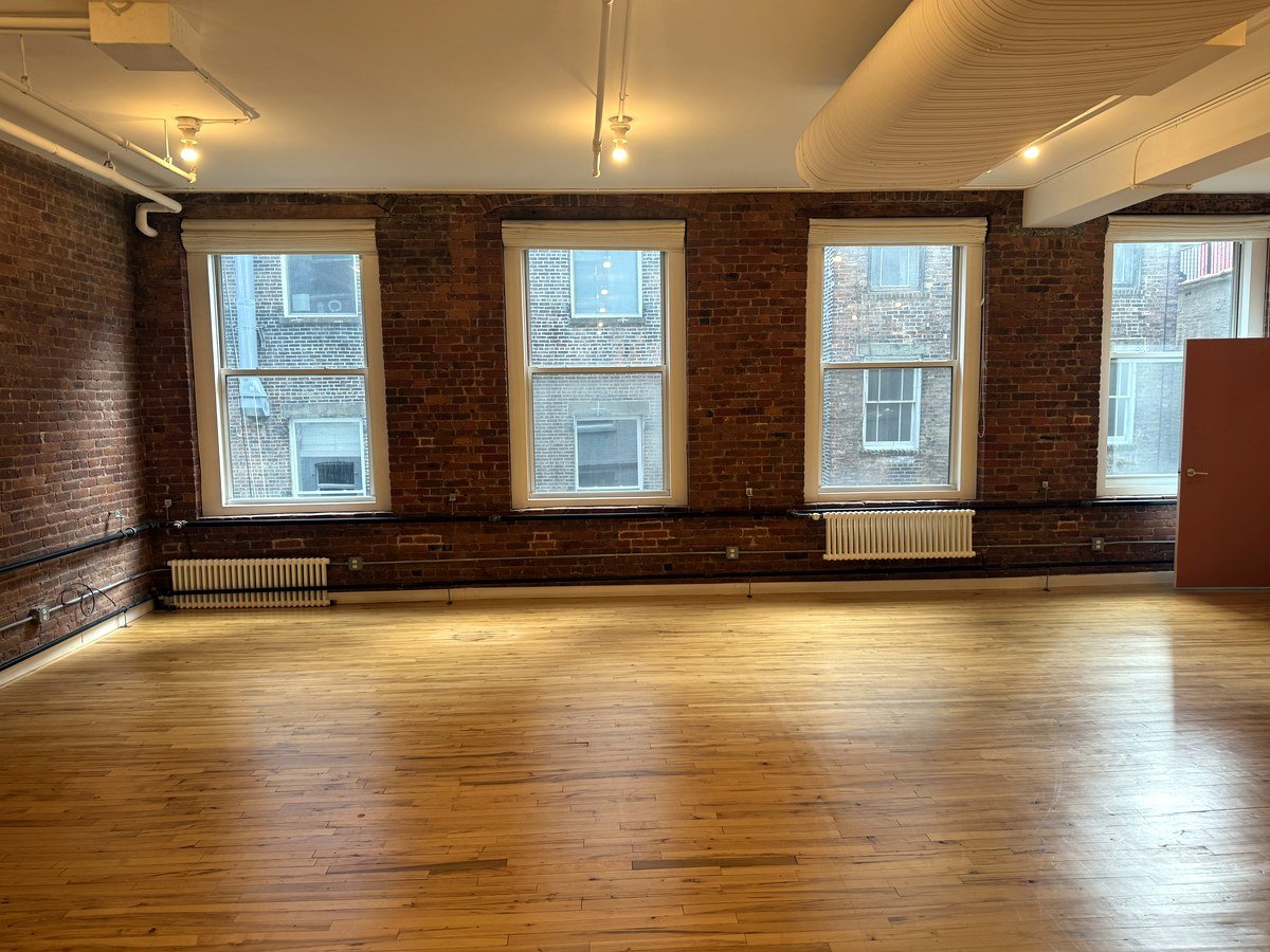 Windowed loft office space with four large windows and exposed brick at 46 Greene Street