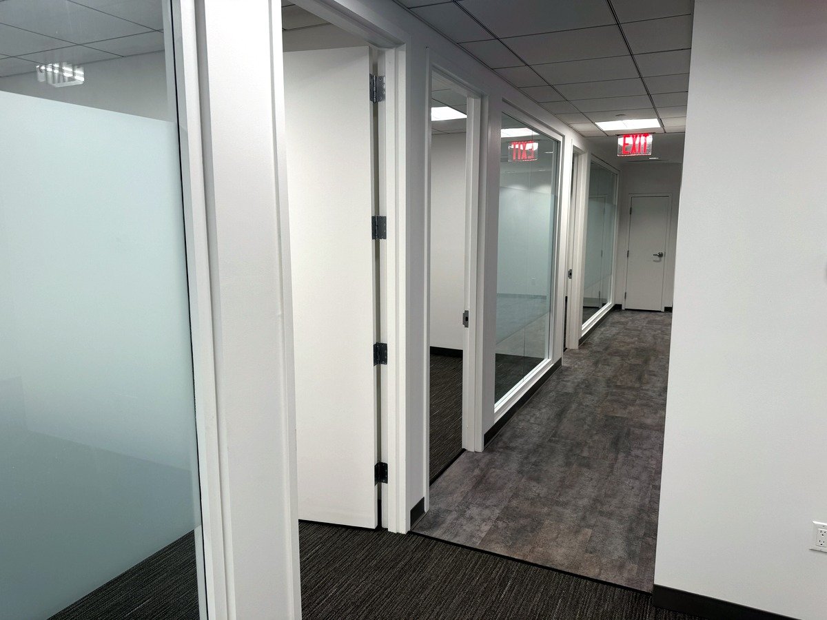 Corridor lined with glass-front private offices, 12th floor at 20 West 55th Street