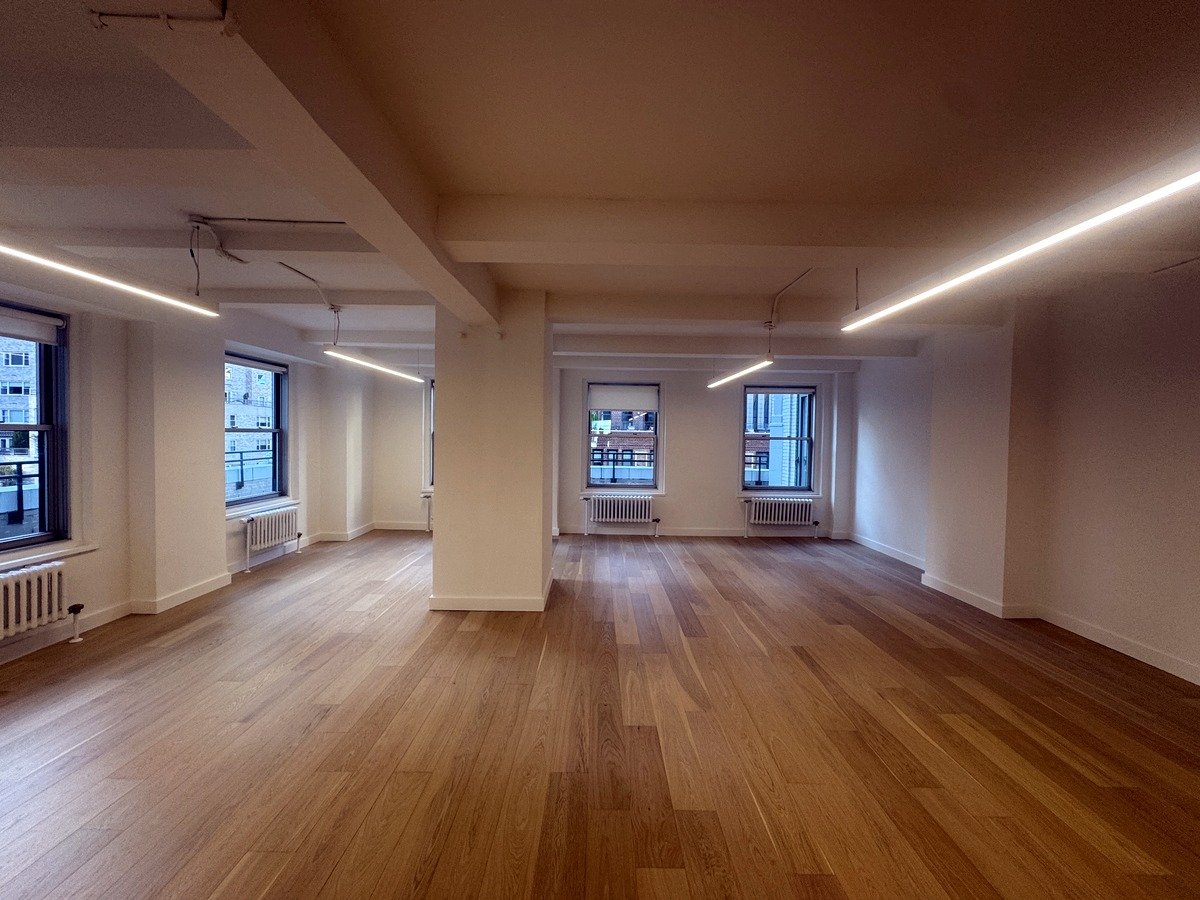 Open loft-style office space with warm hardwood floors and perimeter windows, Suite 1602 at 57 West 57th Street